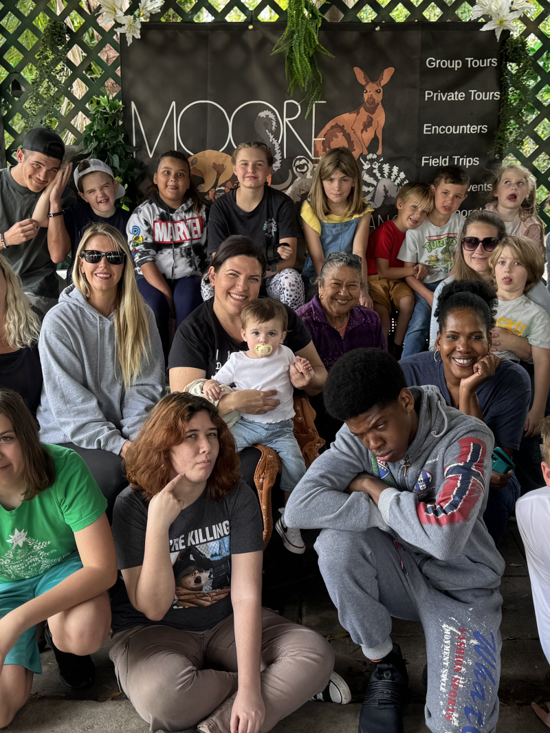 Group of people posing together in front of a zoo sign.
